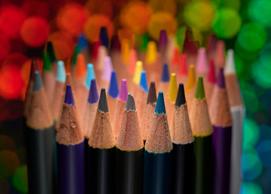 Sharpened colored pencils stand against soft circles of colored light.