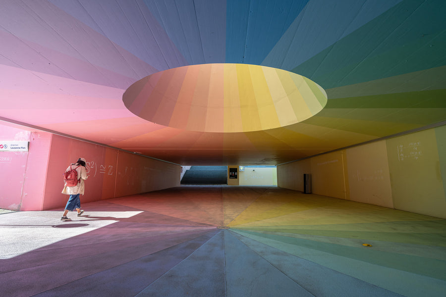 A person stands inside a colorful architectural space beneath a circular ceiling opening.